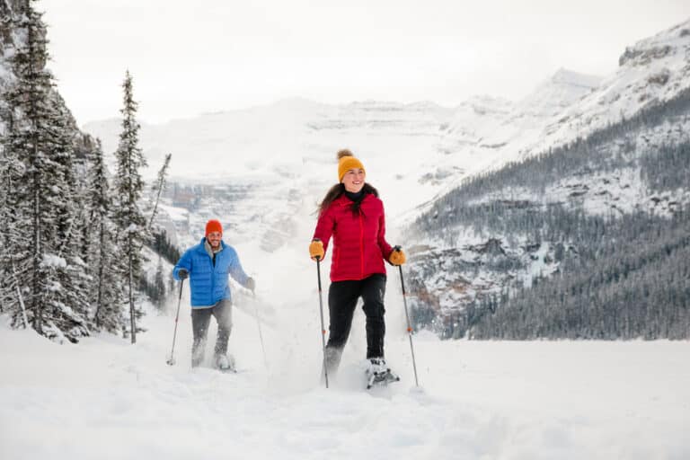 Two guests snowshoeing through fresh powder on a guided snowshoe tour in the Canadian Rockies near Canmore, Alberta